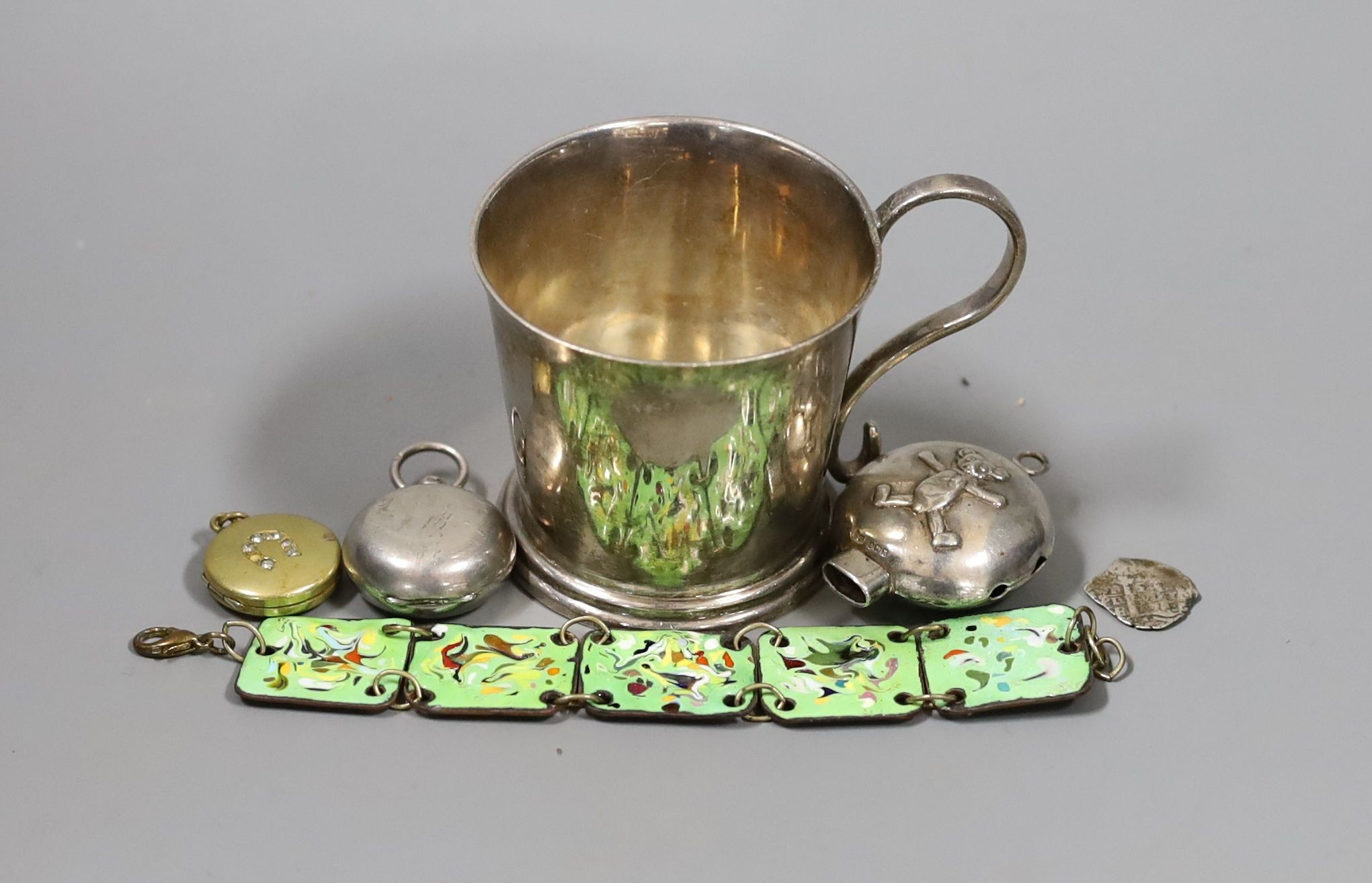 A modern Irish silver christening mug, Royal Irish Silver Co. Dublin, 1974, retailed by Asprey, London, 7cm, a late Victorian silver sovereign case, a gilt metal locket, part of a child's silver rattle and a polychrome e